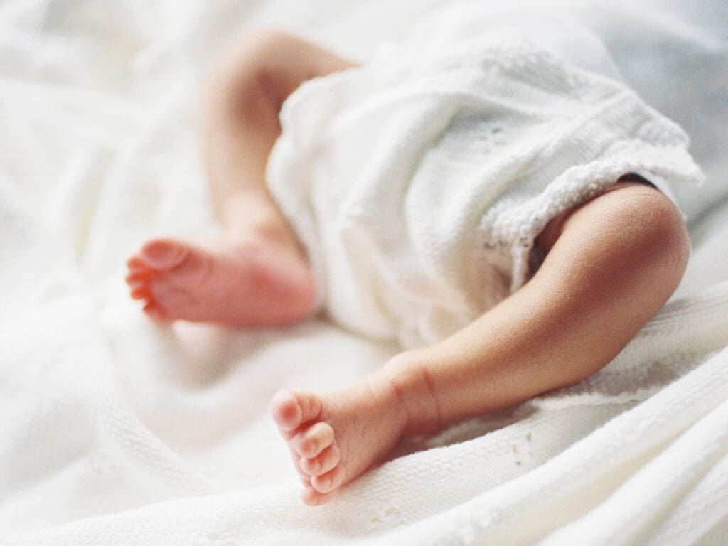 A close-up of a baby's legs and feet as the baby is wrapped in a blanket during a newborn photography session in Richmond, Virginia by Katie Stansfield Photography.